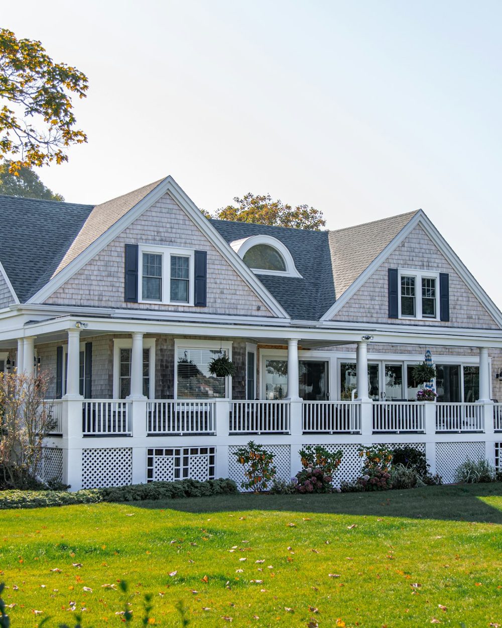 Gray shingle home with a wraparound porch and deep lawn